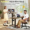 Small electric standing desk set up in a tight room beside a window