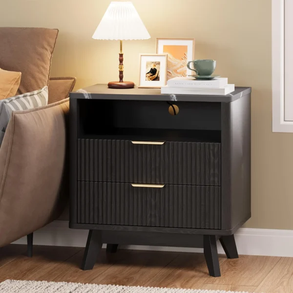 Black mid century bedside table beside a bed with a lamp on top