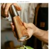 Cylindrical ceramic seasoning grinder and jar set with acacia wood accents, Japanese-style design for black peppercorns and kitchen use.